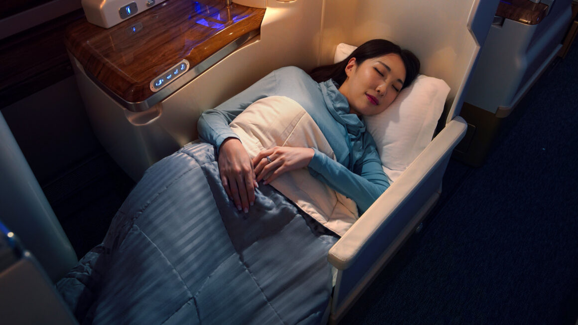 A woman is sleeping/napping wearing Emirates Business Class Loungewear