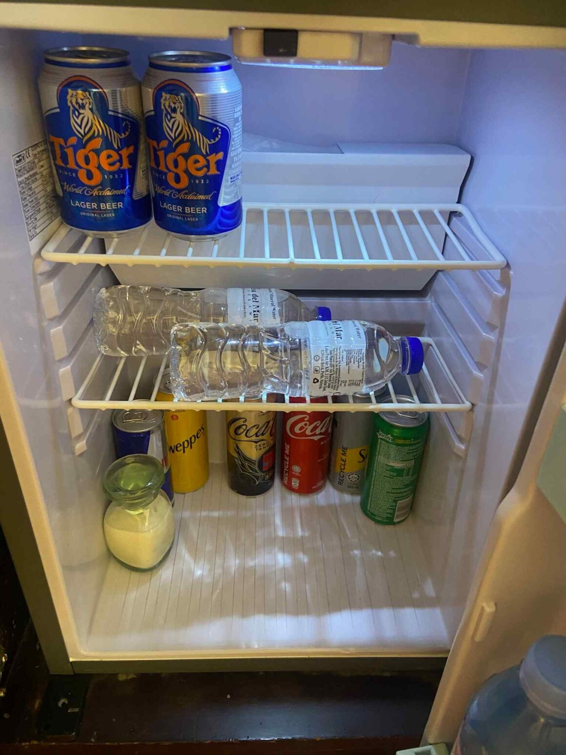A photo of a small fridge with softdrinks and beers.